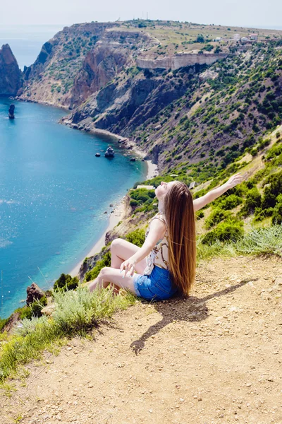 Joven hembra caucásica en un acantilado sobre el mar disfrutando del sol y la libertad —  Fotos de Stock