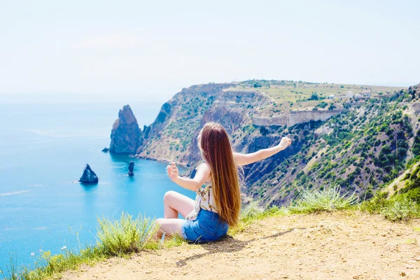 Joven hembra caucásica en un acantilado sobre el mar disfrutando del sol y la libertad —  Fotos de Stock