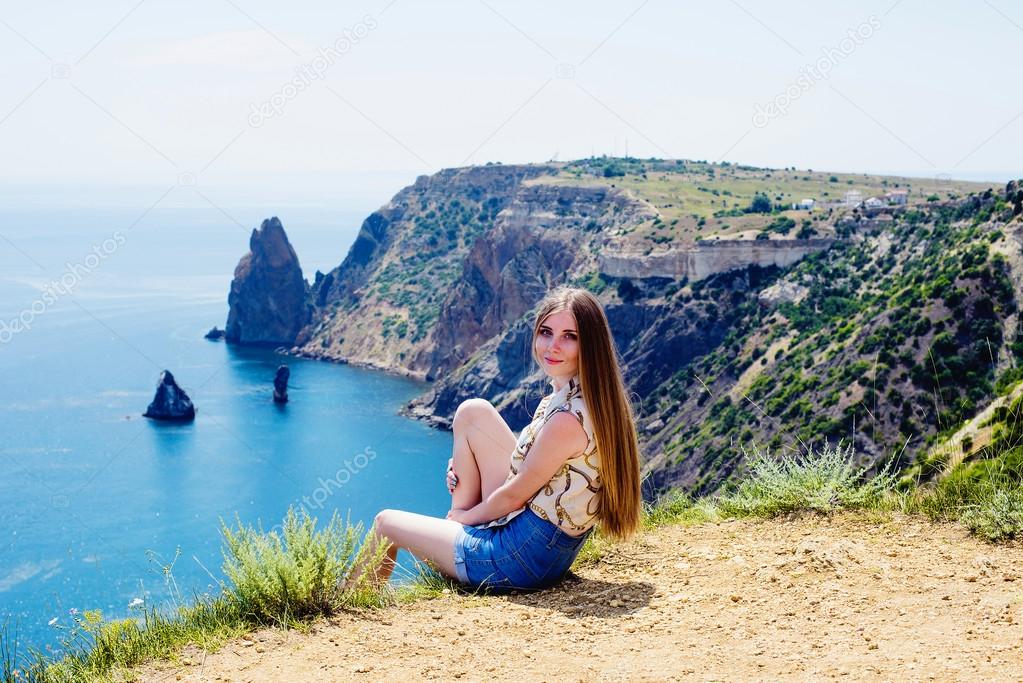 young caucasian female on a cliff above the sea enjoying the sun and freedom