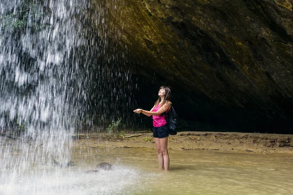 Fiatal kaukázusi nő túrázó a vízesés közelében — Stock Fotó