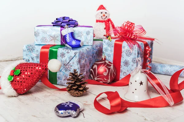 Juldekorationer med inslagna julklappar, fir kottar och klockor på vit trä bakgrund — Stockfoto