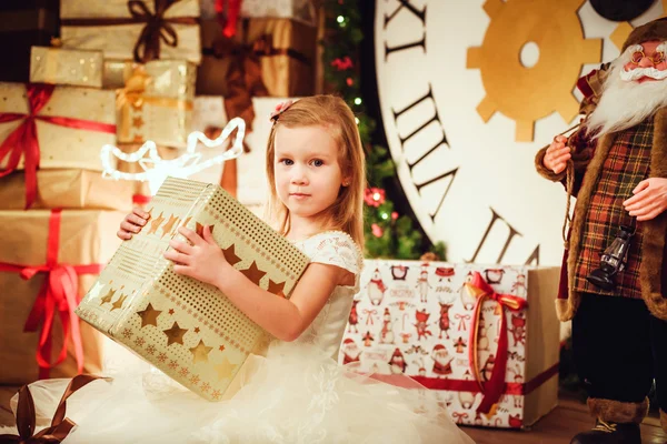 Liten söt flicka med presenterar sitter i juldekorationer — Stockfoto