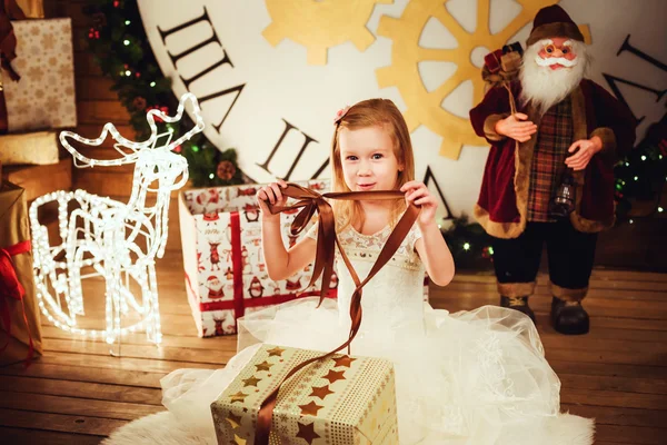 Menina bonita com presentes sentados em decorações de Natal — Fotografia de Stock