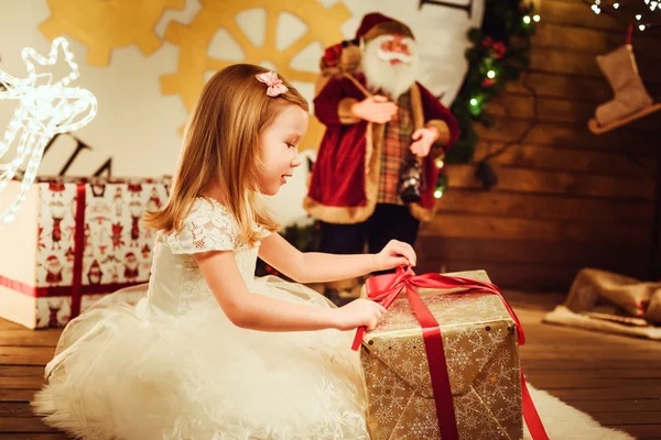 Liten söt flicka med presenterar sitter i juldekorationer — Stockfoto