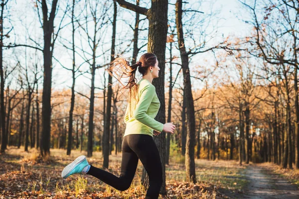 Kvinna i park. Ung kvinna jogging i höst skog — Stockfoto