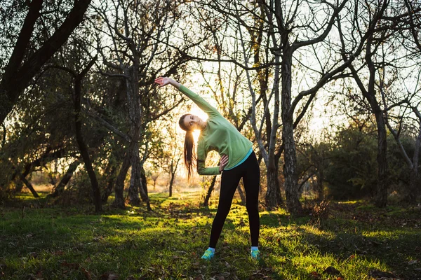 Mujer joven caucásica haciendo ejercicio en el parque durante el amanecer o la puesta del sol — Foto de Stock