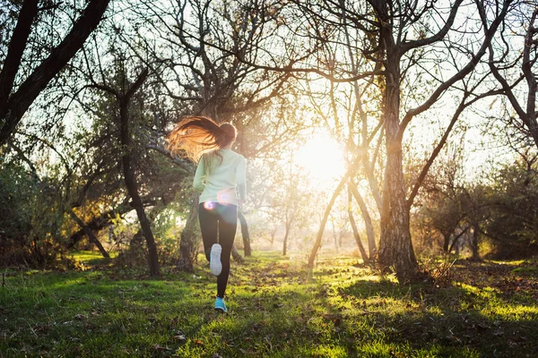 Mujer corriendo en el parque. Mujer joven corriendo en el bosque de otoño — Foto de Stock