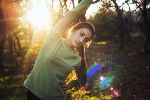 Mujer joven caucásica haciendo ejercicio en el parque durante el amanecer o la puesta del sol — Foto de Stock