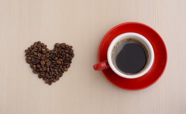 Kahve fincanı kahve çekirdekleri ahşap arka plan üzerinde kalp şeklinde ile yakın çekim.