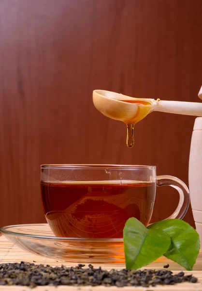 Honey pouring from drizzler into the bowl. Bowl is on a wooden table. — Stock Photo, Image