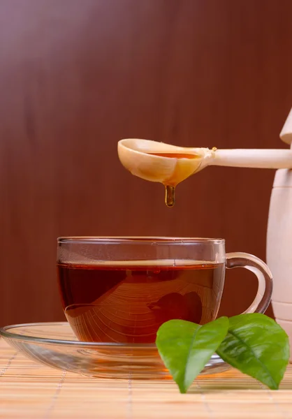 Honey pouring from drizzler into the bowl. Bowl is on a wooden table. — Stock Photo, Image