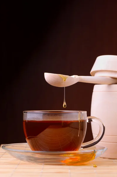 Honey pouring from drizzler into the bowl. Bowl is on a wooden table. — Stock Photo, Image