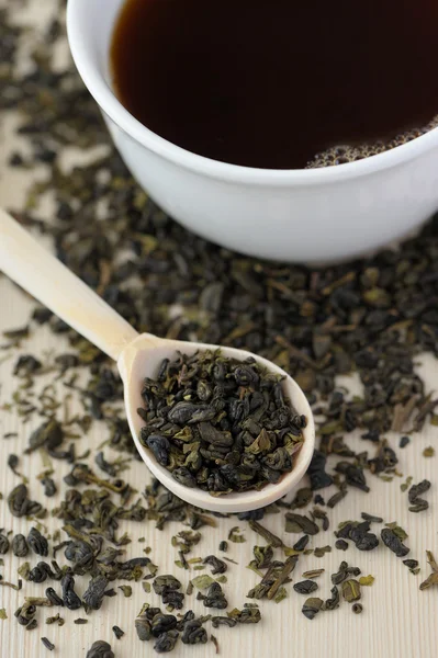 Assortment of dry tea in spoons and cup of tea, on wooden background — Stock Photo, Image