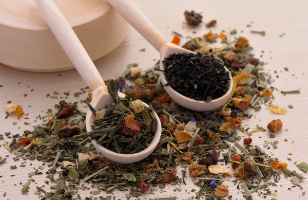 Assortment of dry tea in spoons, on wooden background — Stock Photo, Image