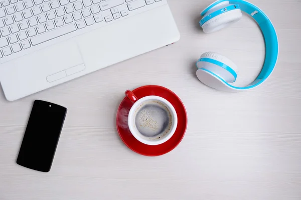 Dizüstü bilgisayar, kulaklık, smartphone ve kahve Kupası ahşap masa üzerinde. Yukarıdan görüntülemek