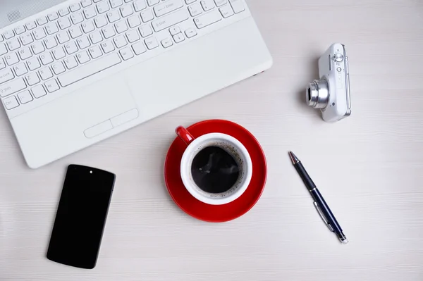 Ahşap masa üzerinde laptop, fotoğraf makinesi, smartphone, kalem ve kahve Kupası. Yukarıdan görüntülemek