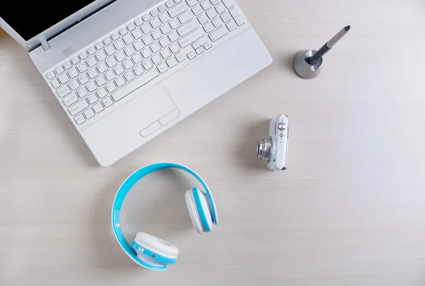 Ahşap masa üzerinde laptop, kalem, kamera, kulaklık ve kahve Kupası. Yukarıdan görüntülemek