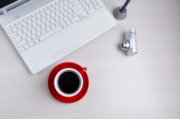 Ahşap masa üzerinde laptop, fotoğraf makinesi, kalem ve kahve Kupası. Yukarıdan görüntülemek