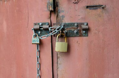 Padlock. Closed iron door. Rusty surface. Metal chain.