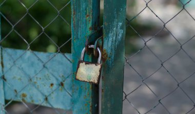 Kapıda asma kilit var. Demir kapı. Çatlak boya..