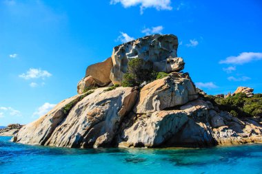 Gün batımında mavi bir denizin yanında kayalar.