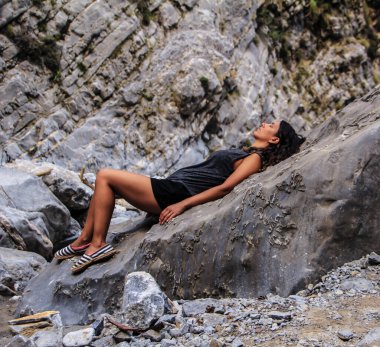 Çekici Latin kız bir kayanın üzerinde dinleniyor