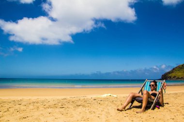 Latin kız plajda hamakla güneşleniyor.