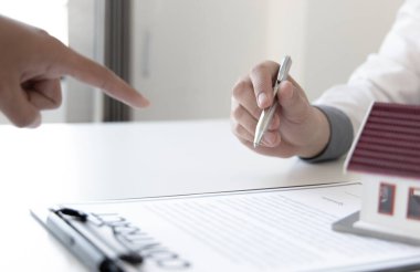 Emlakçı ya da satış müdürü, ev satın alma anlaşmalarını sigorta ile imzalayan müşterilere satın alma sözleşmesini imzalama şartlarını ve şartlarını önerdi..