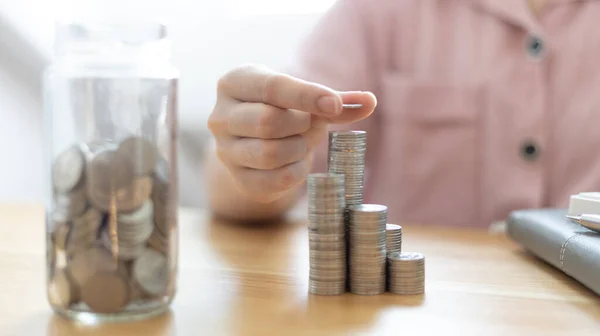Woman\'s hands put the coins arranged in steps, Managing your finances or saving money for future use, Saving for investment, Saving money for business growth or long-term profitability.