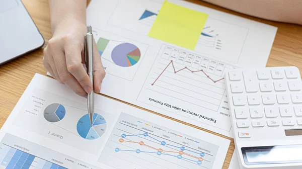 Businessmen working in the office using the expense and budget accounting calculator with graphs as a measure of the company's growth, financial and accounting concepts.