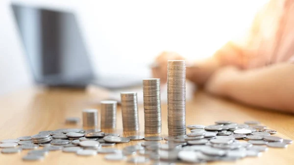 Eğik bir grafiğe yerleştirilmiş dolar sikkeleri, hesap makinesine basan bir iş kadınının bulanık görüntüsü, mali iş büyümesi, iş büyümesi veya uzun vadeli kazanç için tasarruf etmek, para tasarrufu..