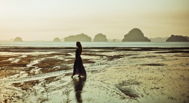 Deniz kaya üzerinde duran ve bir güneş arayan genç bir kadın