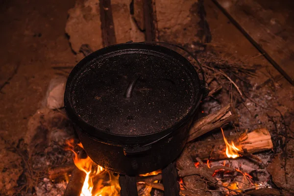 Geceleri yanan kamp ateşinde kazanda yemek pişirmek. — Stok fotoğraf