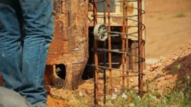 Traktör çelik çubuk asansörleri ve yerdeki bir deliğe koydu. İnşaat İşçileri ona yardım ediyorsun.