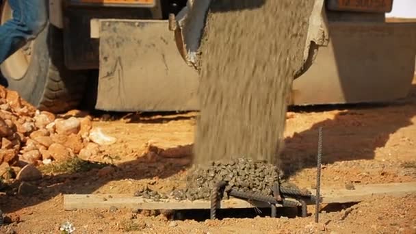 Pracowników budowlanych wylewanie betonu do dziury w ziemi z konkretnych betonomieszarek w budowie. — Wideo stockowe