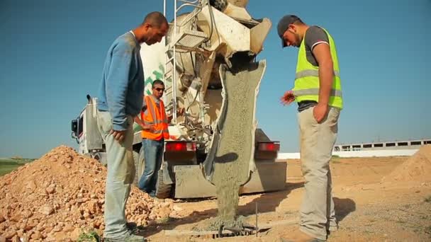 İnşaat İşçileri dökme beton yerdeki bir delik için Beton mikseri kamyonu inşaat sahasında üzerinden. — Stok video