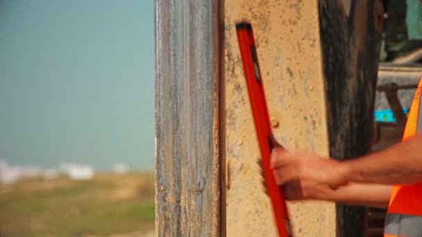 Tractor con un dispositivo de perforación en un sitio de construcción. Trabajadores de la construcción comprobando mediciones . — Vídeos de Stock