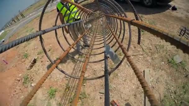 Traktoru výtahy ocelová tyč a dát ji do díry v zemi. Stavební dělníci mu pomáhají. — Stock video