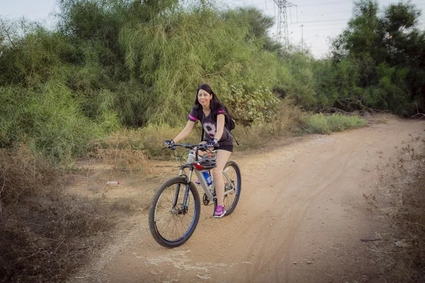 在乡下骑自行车，看着相机的女人 — 图库照片