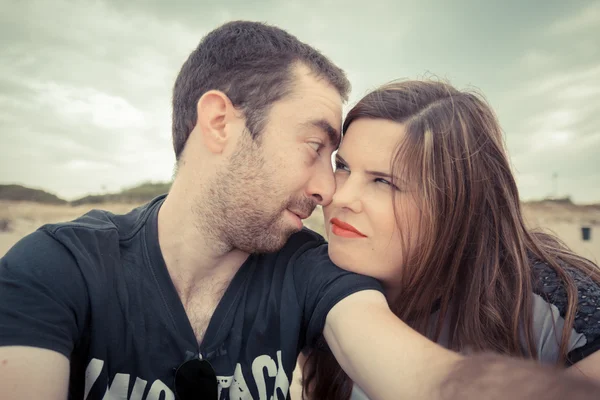 Pareja joven tomando selfie con smartphone o cámara en la playa — Foto de Stock