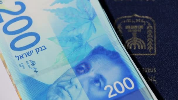 Contas de dinheiro israelitas rotativas de 200 shekel e passaporte israelense vista superior — Vídeo de Stock
