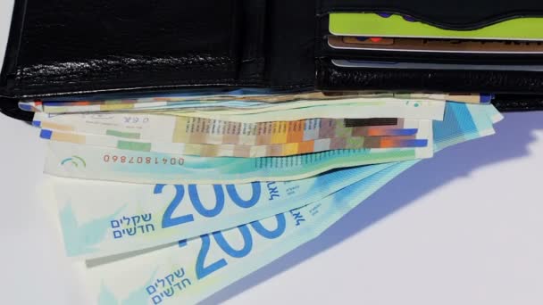 Girando varios billetes de dinero shekel israelíes en cartera de cuero negro abierto - vista superior — Vídeos de Stock