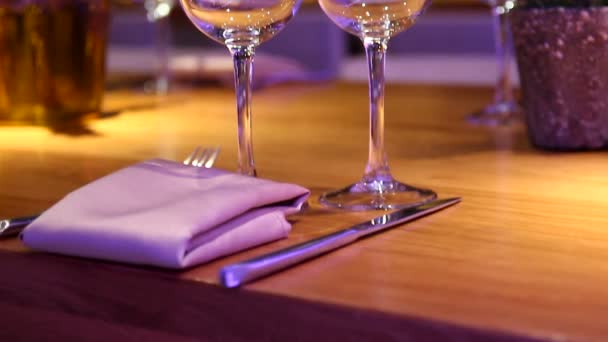 Empty wine glasses on a wooden table at a restaurant - Tilt up — Stock Video