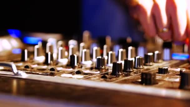 Mãos de DJ ajustam vários controles de faixa no console do mixer de DJ na boate — Vídeo de Stock