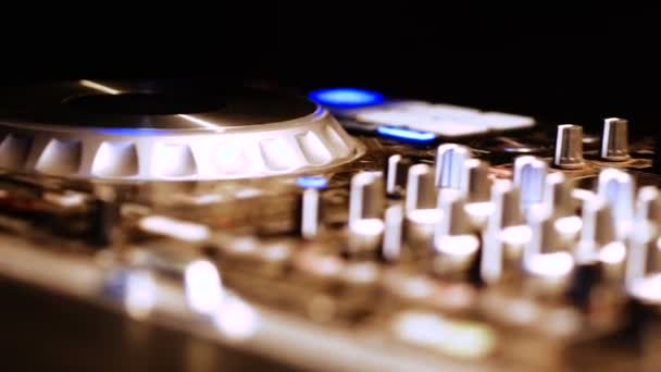 Hands of DJ tweak various track controls on DJ mixer console at nightclub — Stock Video