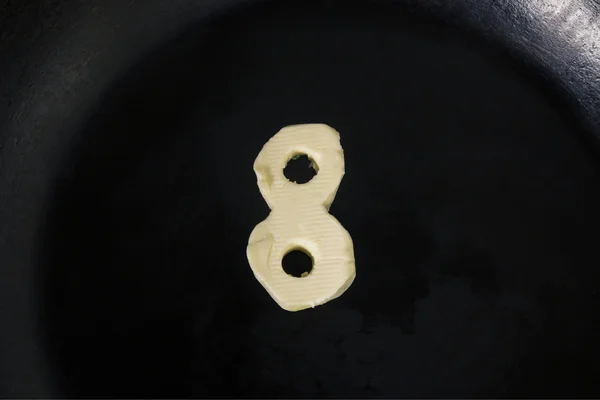 Масло в форме числа 8 на горячей сковороде - Закрыть вид сверху — стоковое фото
