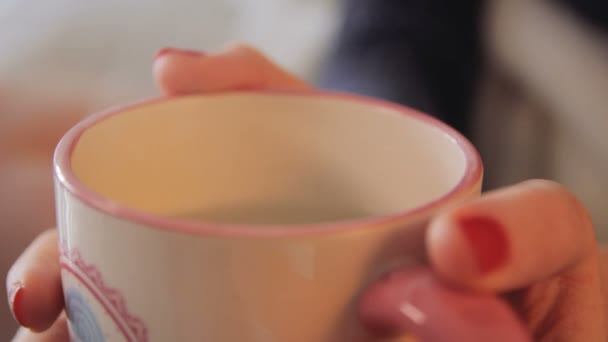 Manos femeninas sosteniendo una taza de té caliente — Vídeo de stock