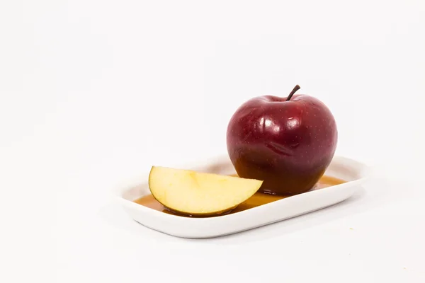 Красное яблоко и красный яблочный ломтик на белой тарелке с медом — стоковое фото