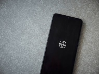 Lod, Israel - 8 Temmuz 2020: Seramik taş zemin üzerinde siyah bir cep telefonunun logosu olan uygulama fırlatma ekranını yansıt. Üst görünüm düzlüğü kopyalama alanı ile yatıyordu.