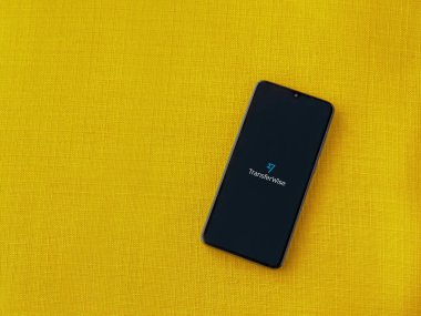 Lod, Israel - 8 Temmuz 2020: Sarı kumaş arka planda siyah bir cep telefonunun logosu olan TransferWise uygulama başlatma ekranı. Üst görünüm düzlüğü kopyalama alanı ile yatıyordu.